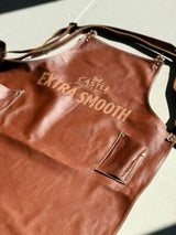 Brown leather apron with ’castle double malt extra smooth’ branding in tan lettering.