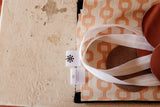Orange and cream geometric-patterned tote bag with white fabric handles.