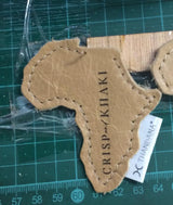 Tan leather africa-shaped patch with stitched edges and embossed text.
